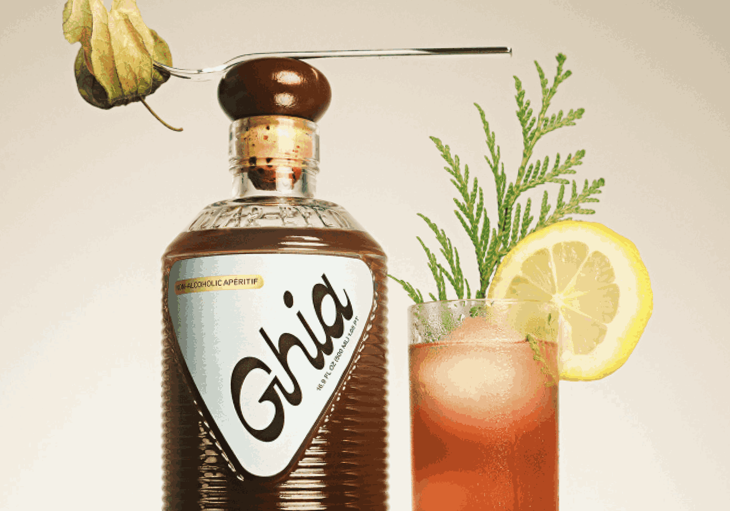 Ghia apéritif bottle with a spoonful of gooseberries resting on the cap beside a spritz garnished with lemon and herbs