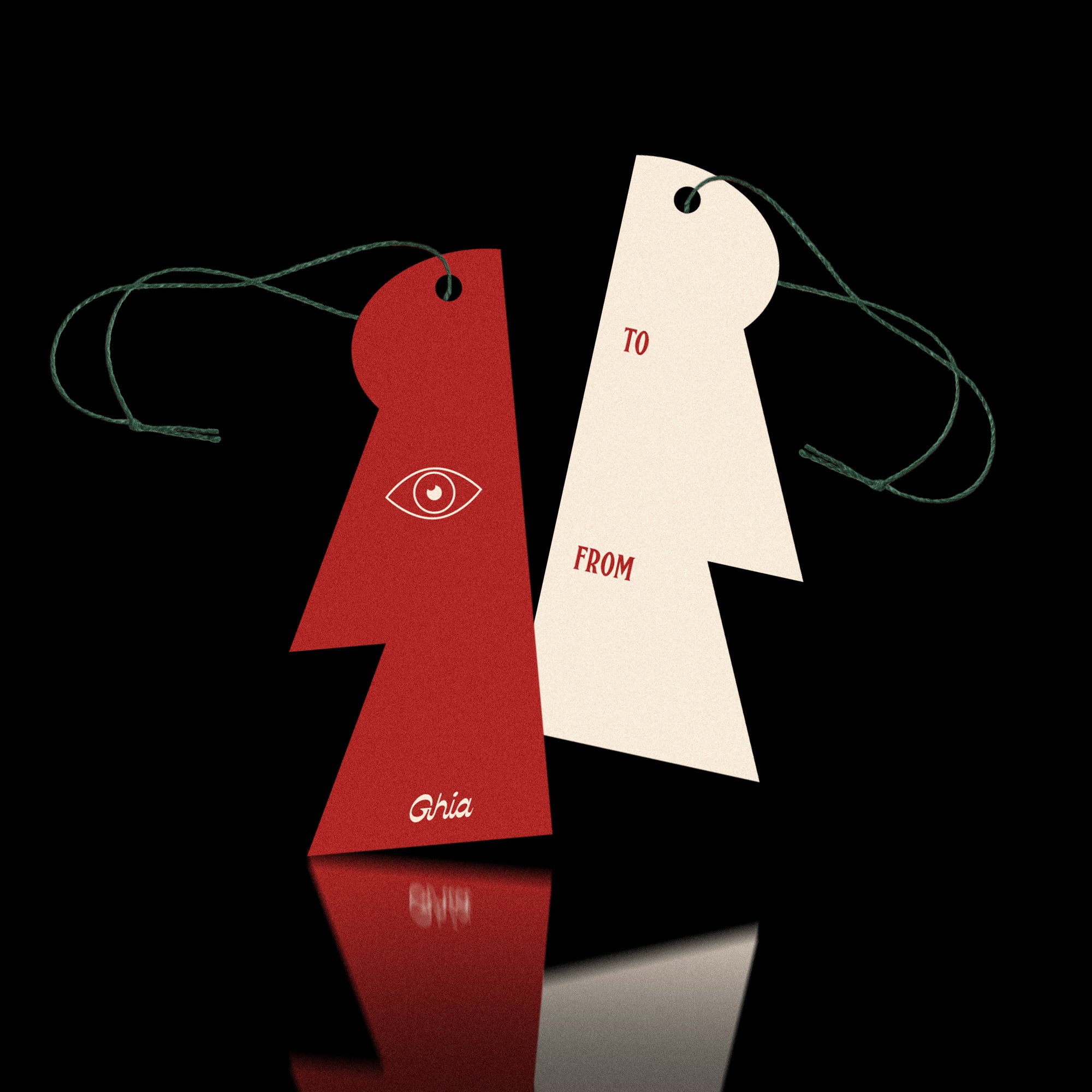 Two Ghia gift tags on green string, one red with an eye illustration and one cream with To and From fields