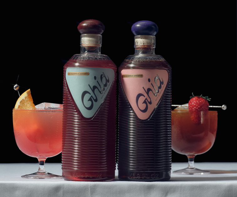 Ghia Original and Berry aperitif bottles flanked by spritzes garnished with orange and strawberry