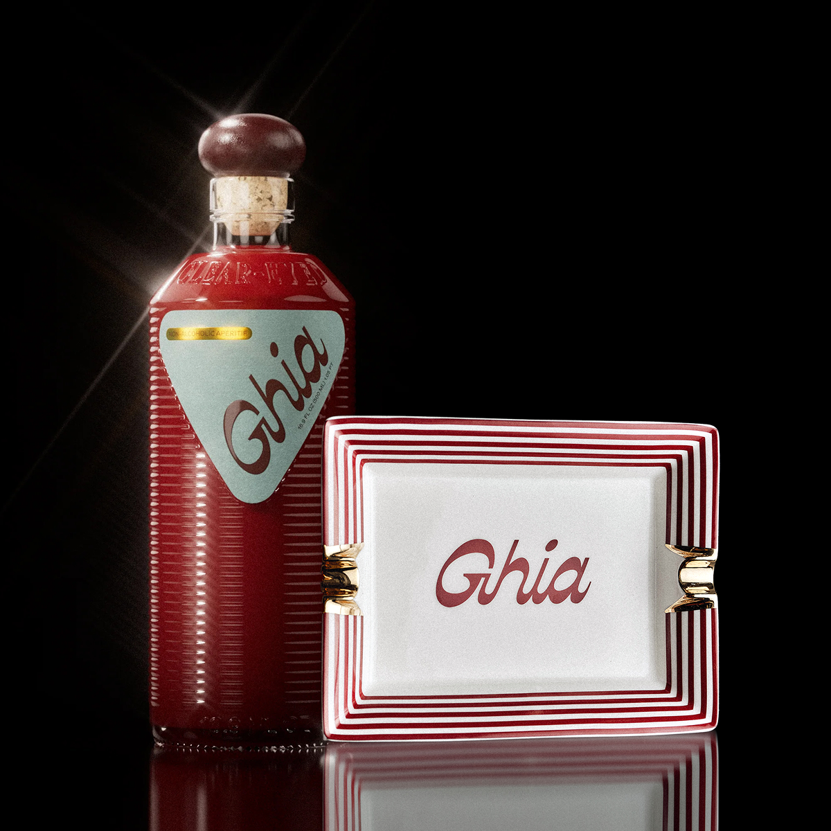 Ghia apéritif bottle beside the red and white striped Ghia vide-poche ceramic tray